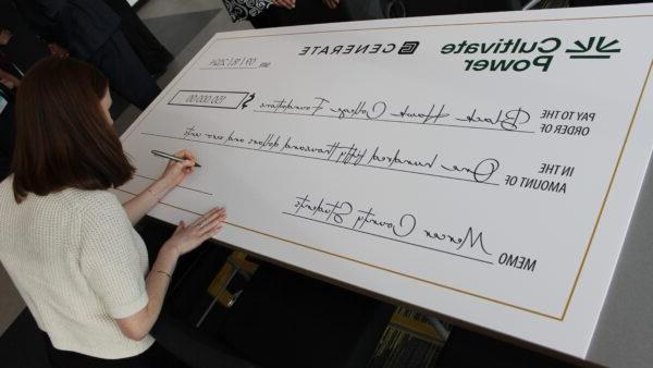 woman signing oversized check